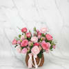 Pink rose and ranunculus arrangement in a wicker basket with a ribbon