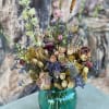 Dried flower bouquet in a teal glass vase