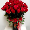 Red roses arranged in a black rectangular vase with a red ribbon