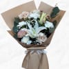 Bouquet of pale roses, white lilies, and chrysanthemums wrapped in tan paper