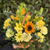 A vibrant basket arrangement filled with layered yellow florals and soft greenery