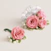 This striking corsage and boutonniere set, featuring delicate light pink blooms, is