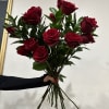 Handheld bouquet of red roses with greenery