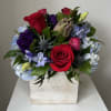 Mixed bouquet of roses, hydrangeas, and purple blooms in a white wooden box