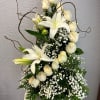 White lilies and cream roses in a white vase with baby's breath