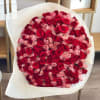 Large round bouquet of red and light pink roses wrapped in white textured paper.