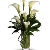 White calla lilies arranged in a clear glass vase