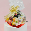 Gift basket with snacks and fruit wrapped in clear cellophane and a gold bow