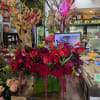 Red and burgundy floral arrangement in a green box with heart decorations