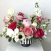 Mixed pink and white flower arrangement in a striped vase