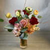 Mixed bouquet of roses, hydrangeas, and anemones in a glass vase