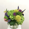 Mixed bouquet in a clear glass vase with green hydrangeas and purple blooms