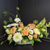 Peach garden roses and airy snapdragons spill from a low white ceramic