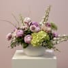 Pink and white floral arrangement in a white bowl vase