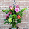 Mixed bouquet in a clear glass vase with pink, purple, and green blooms