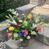 Mixed bouquet of roses, lilies, and irises in a glass vase