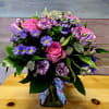 Bouquet of pink roses, purple daisies, and carnations in a glass vase