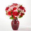 Red and pink mixed bouquet in a red glass vase