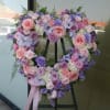 Heart-shaped floral wreath with pink and lavender roses on an easel