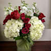 Red roses and white hydrangeas arranged in a glass vase