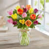 Colorful tulip bouquet in a clear glass vase with a ribbon bow
