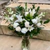White lilies and roses arranged in a clear glass vase