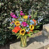 Bright mixed bouquet in a clear glass vase with sunflowers and roses