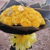 Bouquet of yellow roses wrapped in black paper with a yellow ribbon
