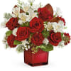 Red roses and white flowers arranged in a red glass vase