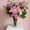 Soft lavender and blush florals arranged in an elegant glass vase with