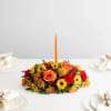 Low floral centerpiece with an orange taper candle
