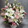 Pink roses and white lilies arranged in a white basket