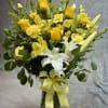 Yellow and white bouquet in a glass vase with a ribbon