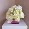 An elegant all-white arrangement featuring hydrangeas, roses, and orchid accents