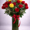 Bouquet of red and yellow roses in a clear glass vase with a red ribbon