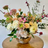 Mixed bouquet of roses, hydrangea, and orchids in a gold bowl vase