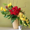 Curly willow, yellow tulips red roses bells of Ireland and orchids hanging