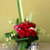 Red roses, purple lisinthus, white hydrangeas in a clear cube vase.