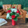 Red ceramic vase displaying a mix of red roses, baby breath 