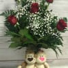 Half dozen red roses, arranged in a glass vase that includes a