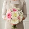A soft hand tied bouquet featuring blush and ivory blooms with a