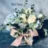 White roses and blue hydrangeas in a glass vase with a burlap bow