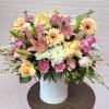 Mixed bouquet of pink and yellow flowers in a white hatbox