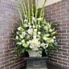 Tall white arrangement with lilies and roses in a basket on a pedestal