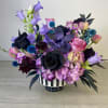Purple and black floral arrangement in a striped vase