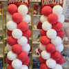 Two tall Christmas balloon columns with red and white balloons and Merry Christmas toppers