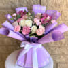 Bouquet of pink and white roses, carnations, and alstroemeria in purple wrap