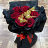 Bouquet of red roses wrapped in black paper with gold butterfly accents
