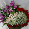 Basket arrangement of red roses, purple stock, and white baby's breath