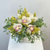 White orchids with yellow filler in a square vase